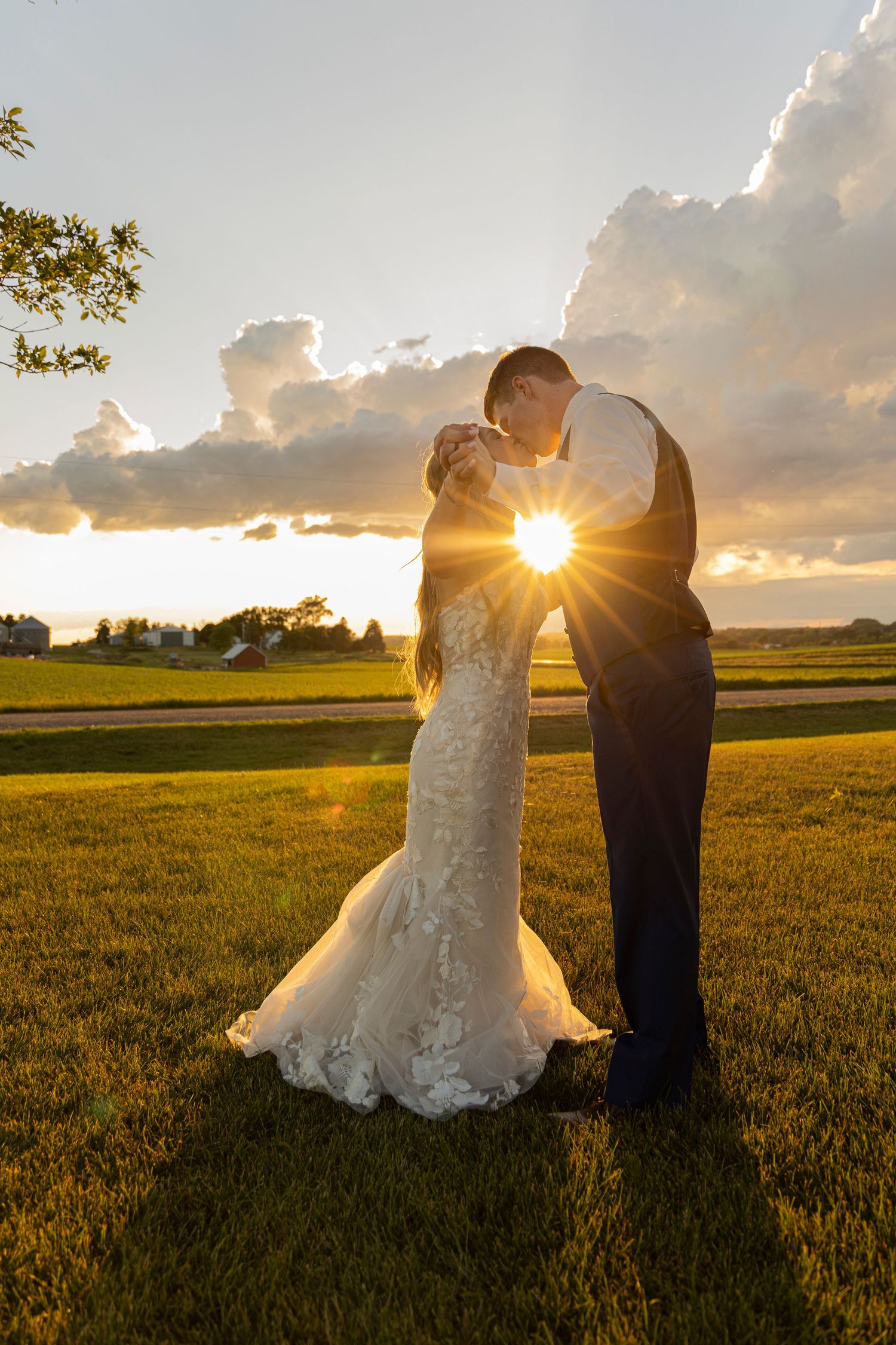 A newly married couple kissing with the sunset behind them at Lofted View Events in Bronson, Iowa.