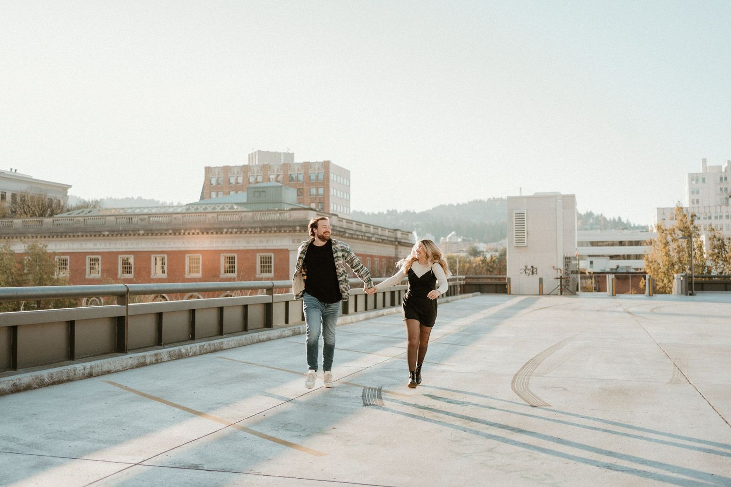 Silhouettes of people walking on a rooftop against a bright sky.