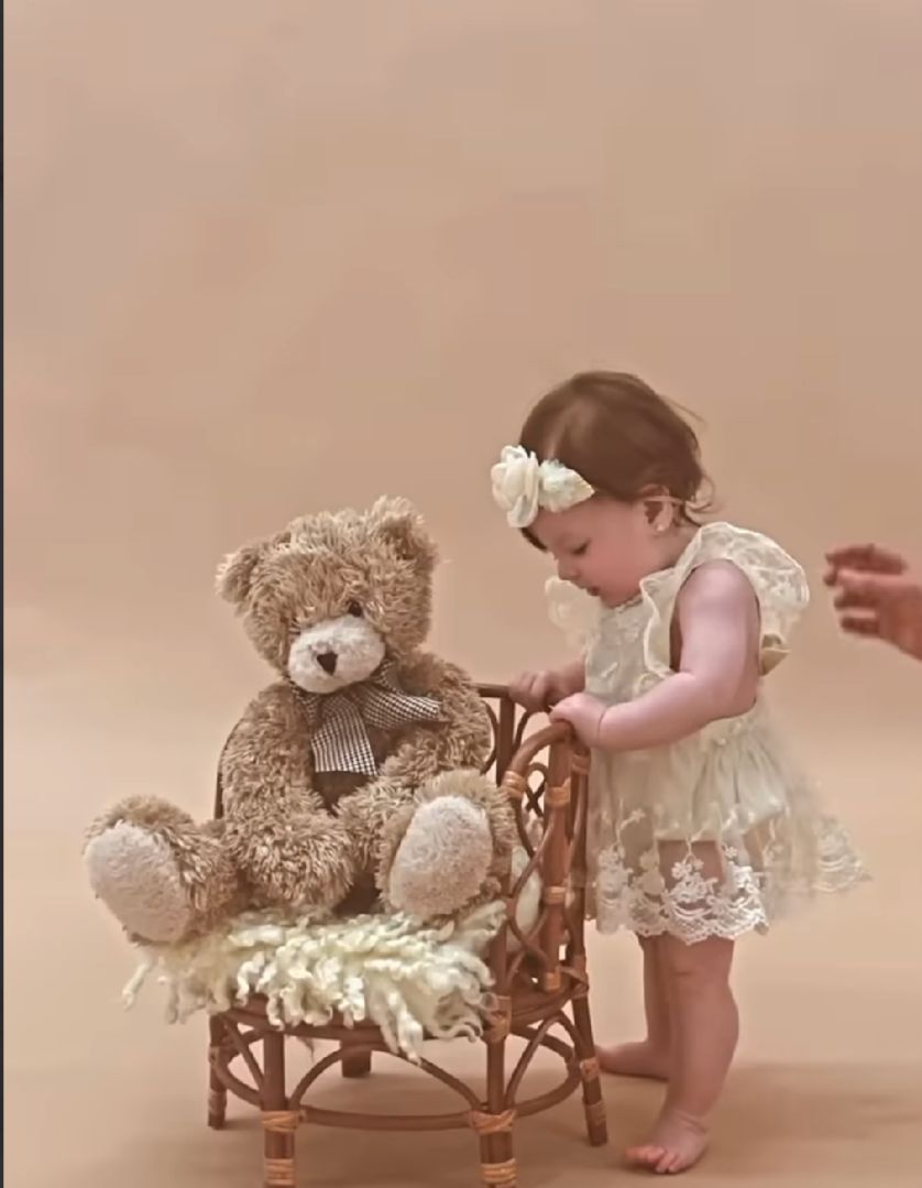 A series of connected photos showing a baby in a white dress interacting with teddy bears on wooden furniture.
