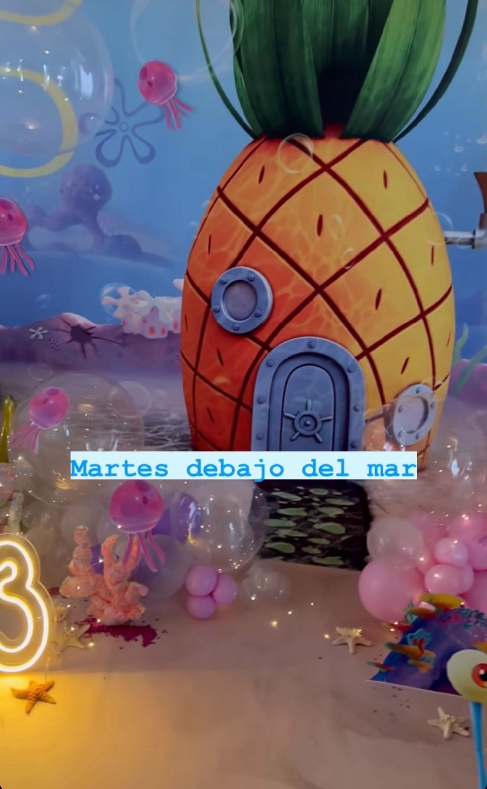 Underwater themed party display with pineapple house decor and pink jellyfish against a blue background.