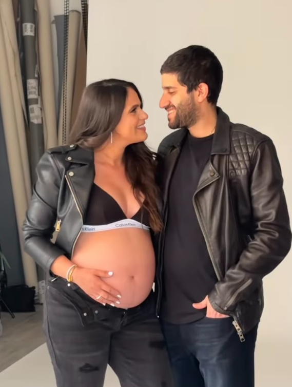 A couple in matching black outfits share tender moments during a maternity photoshoot, showing the pregnant belly.
