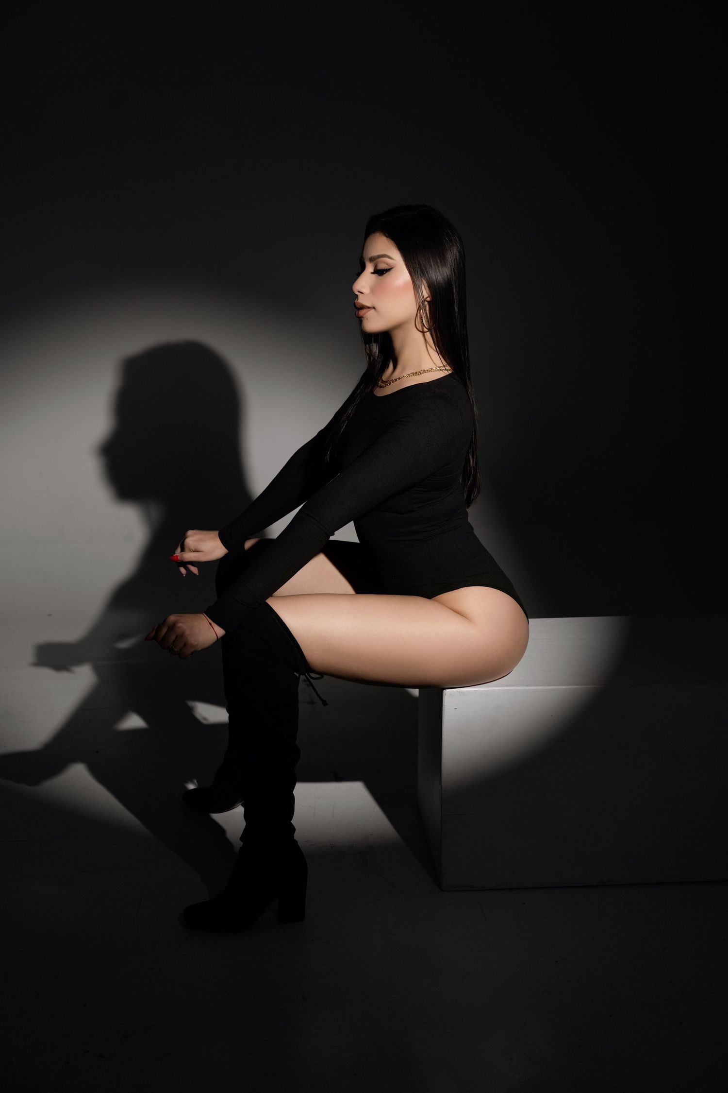 Artistic black and white photo series showing silhouettes of a person in black clothing posing against a light backdrop.