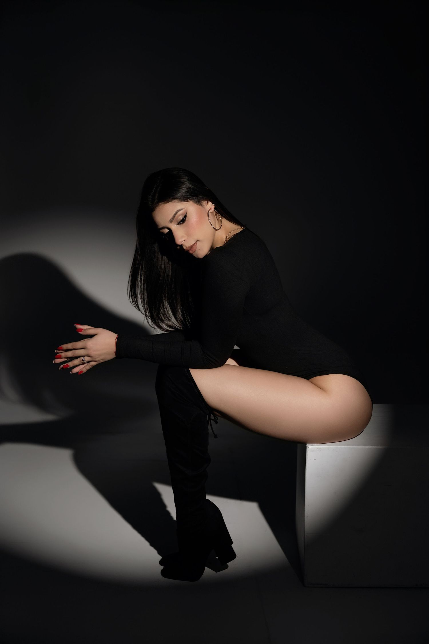 A dramatic black and white photo series showing a person in dark clothing crouching against a stark white background.