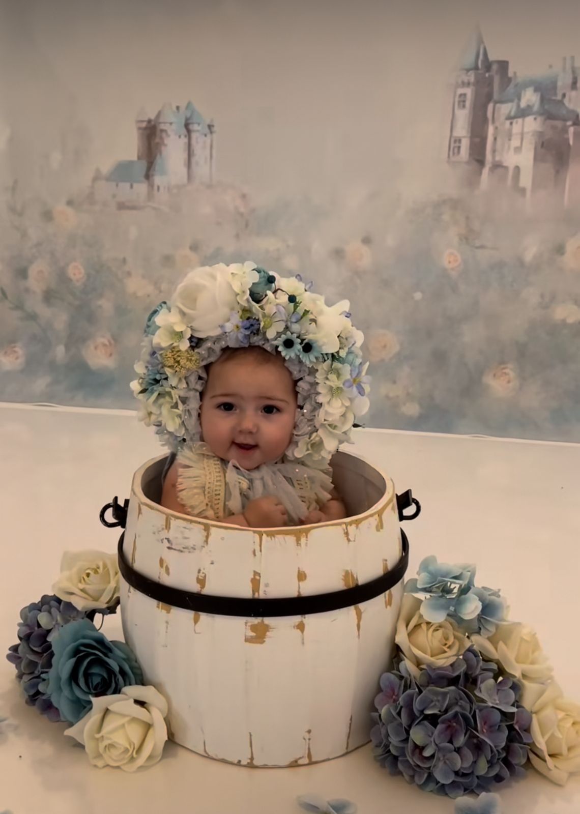 A decorative white wooden basket with blue and cream flowers sits against a soft neutral background.