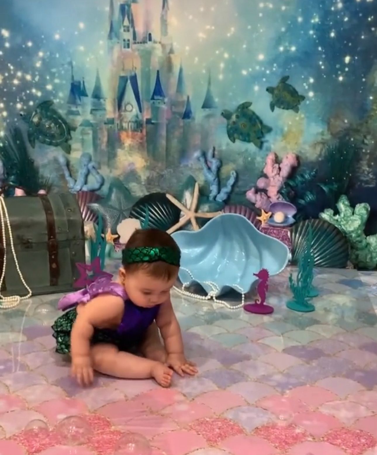 A sequence of images showing a baby crawling on a sparkly pink and blue floor in a magical castle-themed setting.