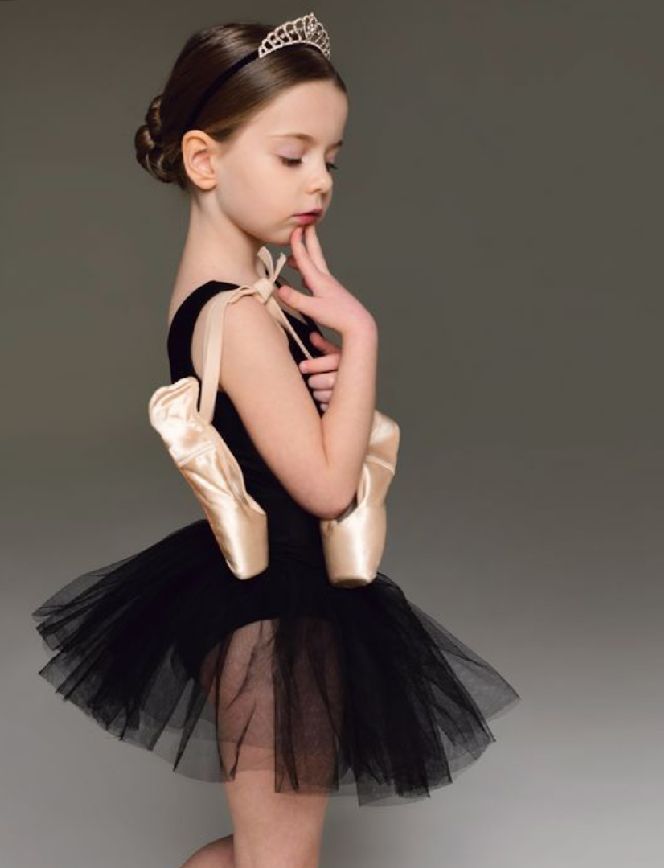 A young ballerina in a black tutu and tiara strikes graceful poses in a series of artistic studio portraits.