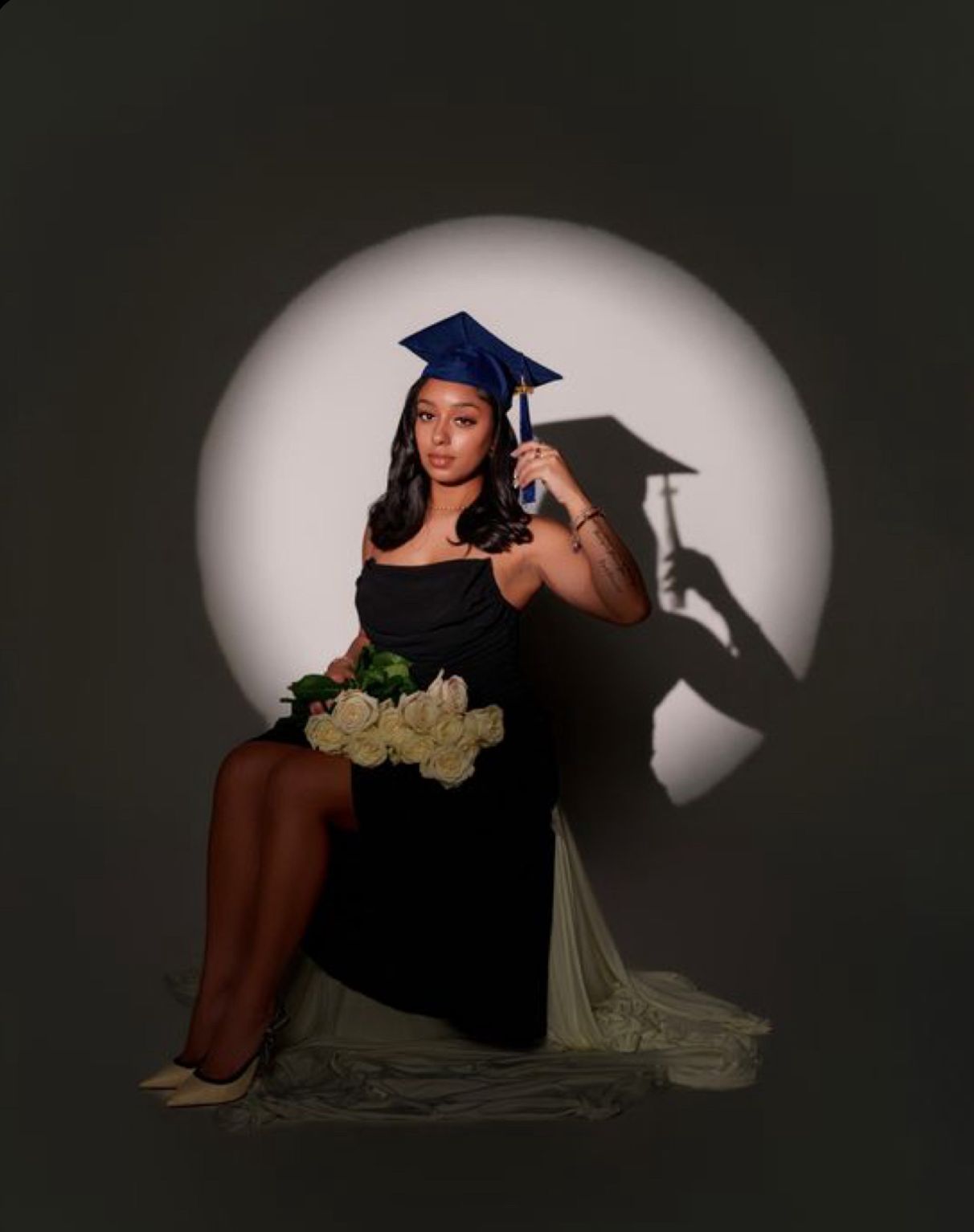 A series of artistic graduation photos in dramatic lighting showing a graduate in a cap and gown posing against a dark background.