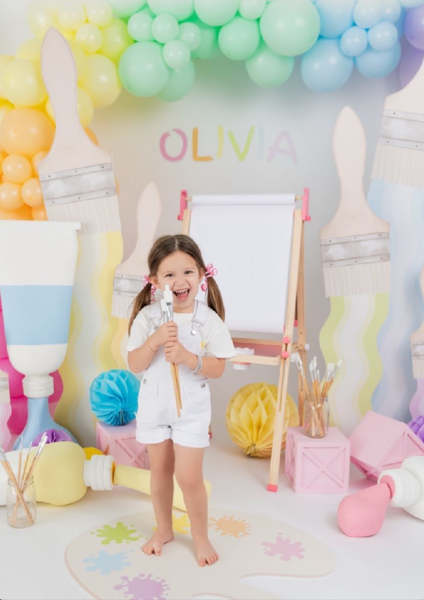 Pastel balloon garland decorates a whimsical party setup with soft colors and festive party decor against a white backdrop.