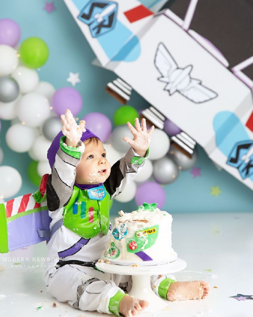 Toy Story themed party decorations with Buzz Lightyear figures and balloon garlands in silver and pastel colors.