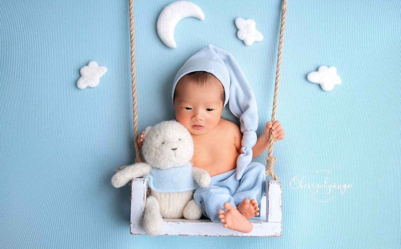A series of five blue-toned newborn photos showing a sleeping baby with soft white props and accessories.