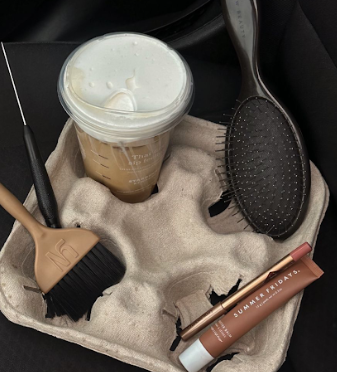 Black gloved hands hold various skincare products and tools against a beige textured background.