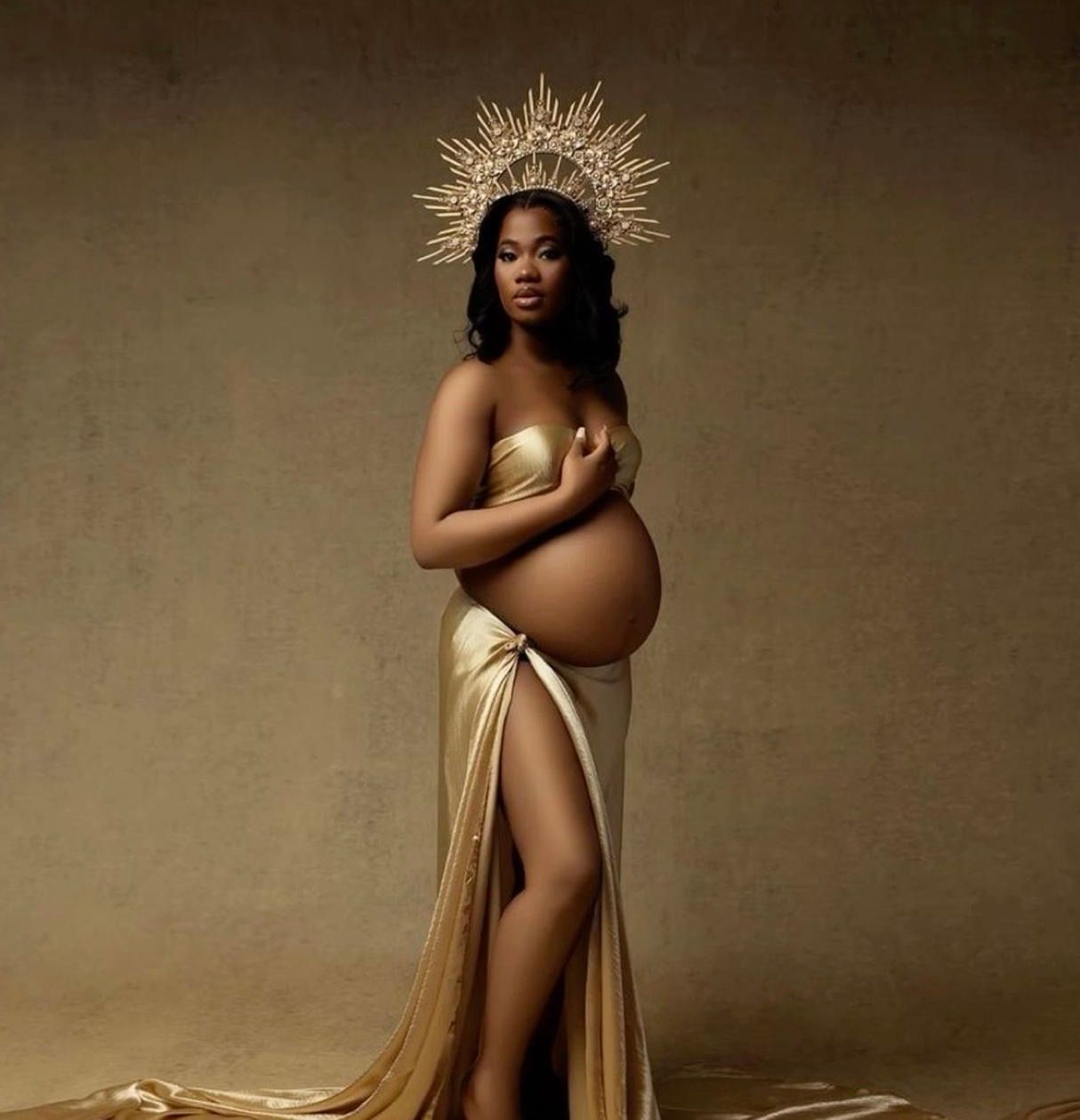 Pregnant woman in gold maternity gown with sunburst crown posing elegantly for a professional maternity photo shoot.