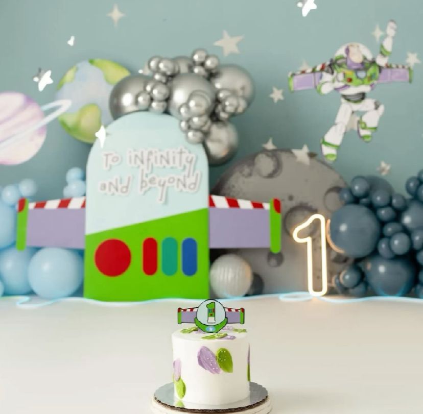 Toy Story themed birthday party setup with balloon garlands and decorations in silver, blue, and green colors.