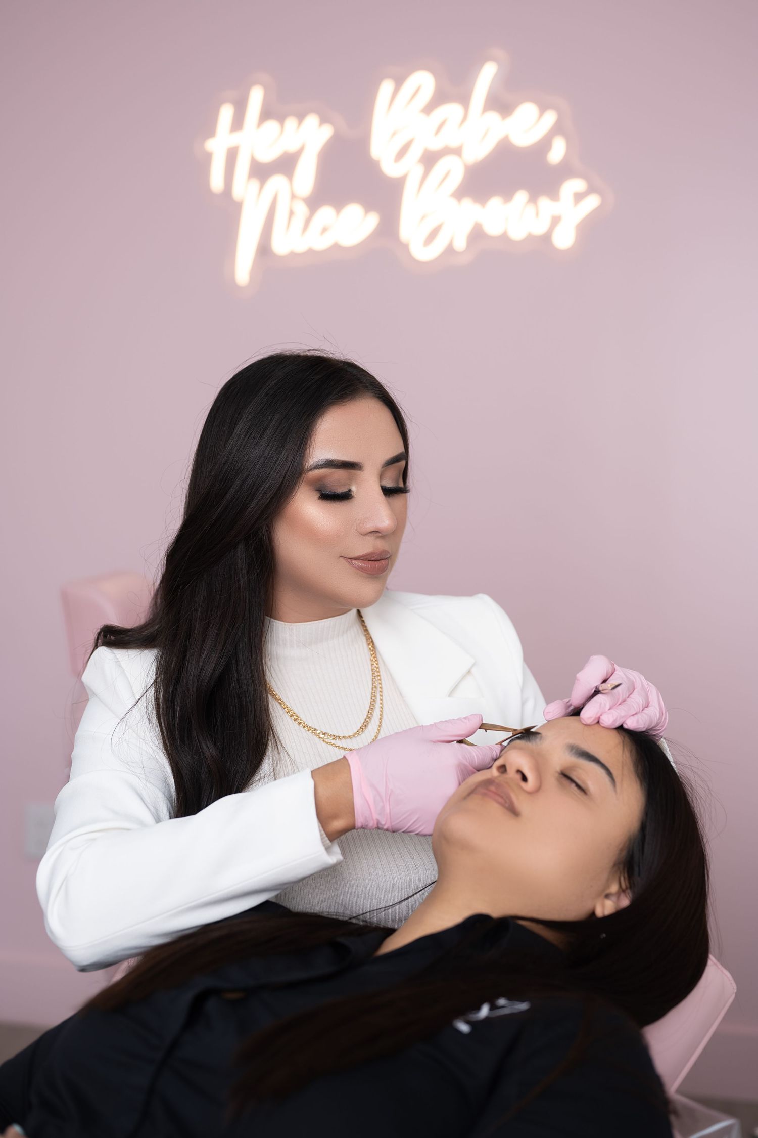 Beauty treatment session shown under pink neon sign illumination.
