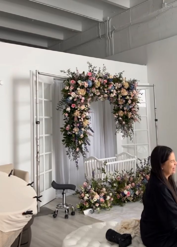 A bright white photography studio space with floral arrangements and natural lighting through large windows.