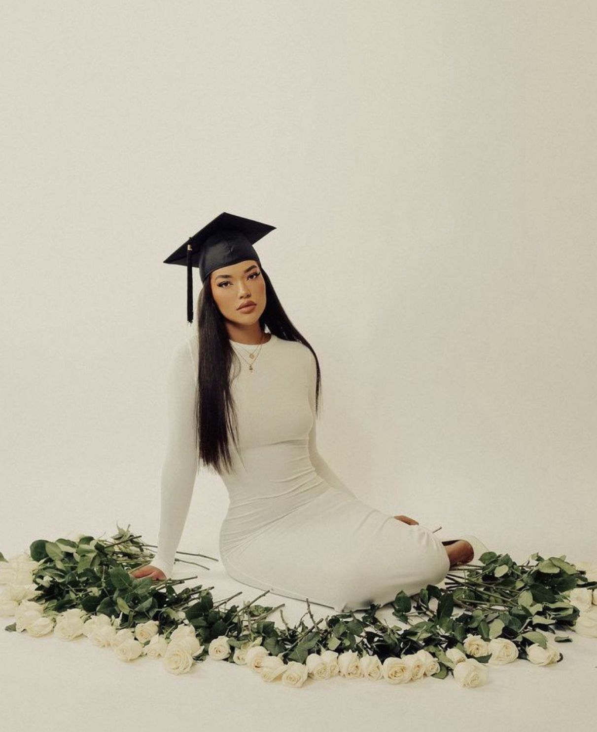 Artistic graduation portrait series with white roses and cap against neutral background.
