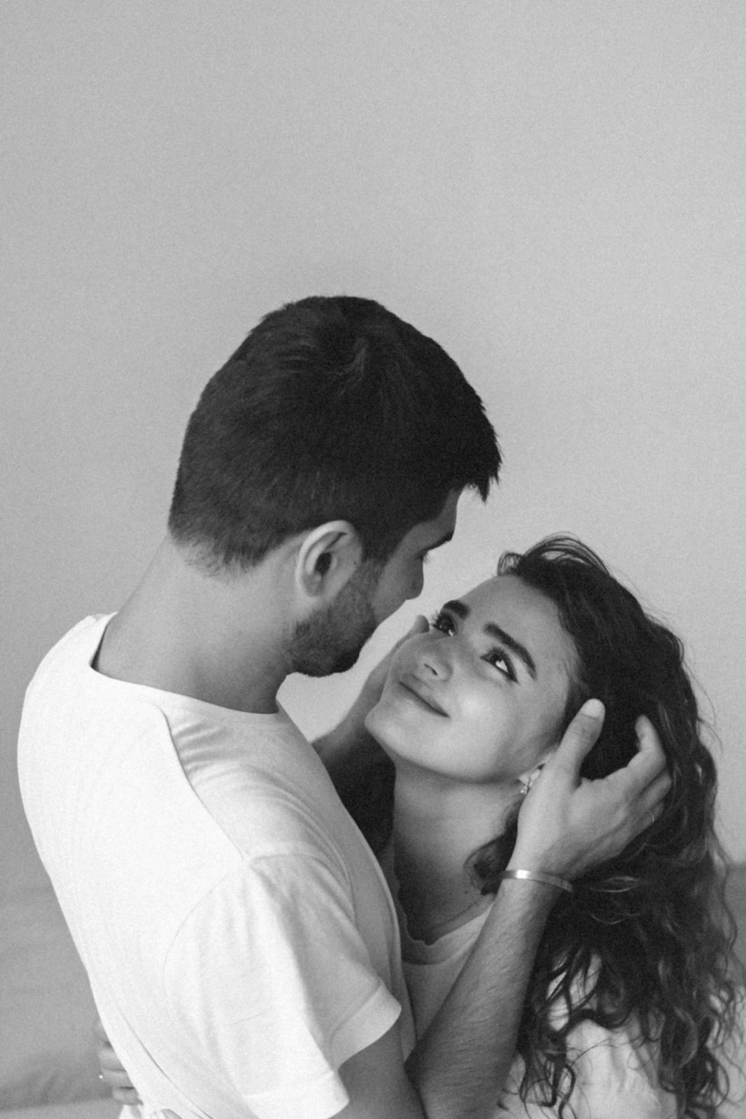 Black and white photo of a romantic couple embracing, man gently holding womans face as she smiles up at him.