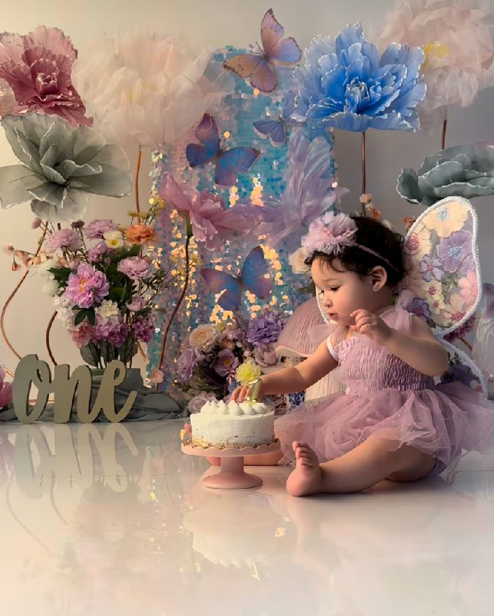 Dreamy cake smash photo session setup with pastel flowers, balloons, and soft pink and blue decorations for a first birthday.