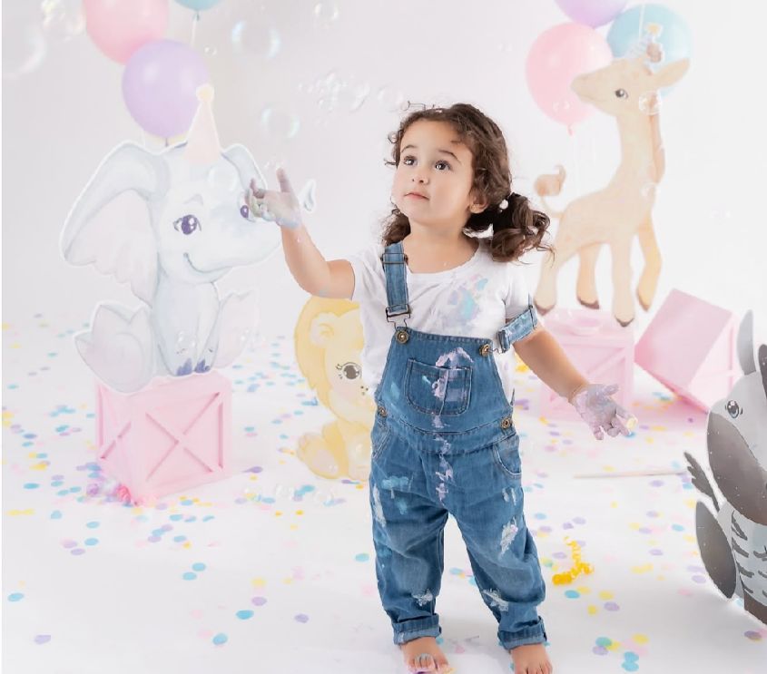 A whimsical party scene with unicorn decorations, pastel balloons, and scattered confetti on the floor.