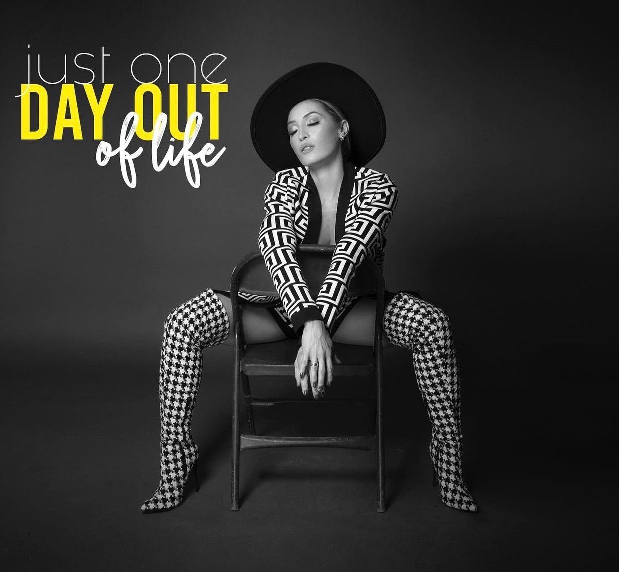 Black and white album cover for Just One Day Out of Life featuring a woman in houndstooth outfit and wide-brim hat seated on a chair.
