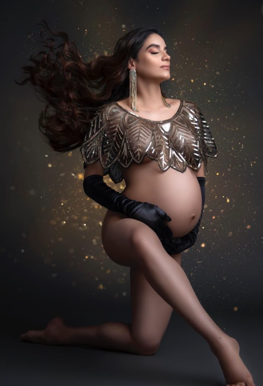 Artistic maternity photo series showing a woman in a sheer gown with flowing hair against a dark background with sparkles.