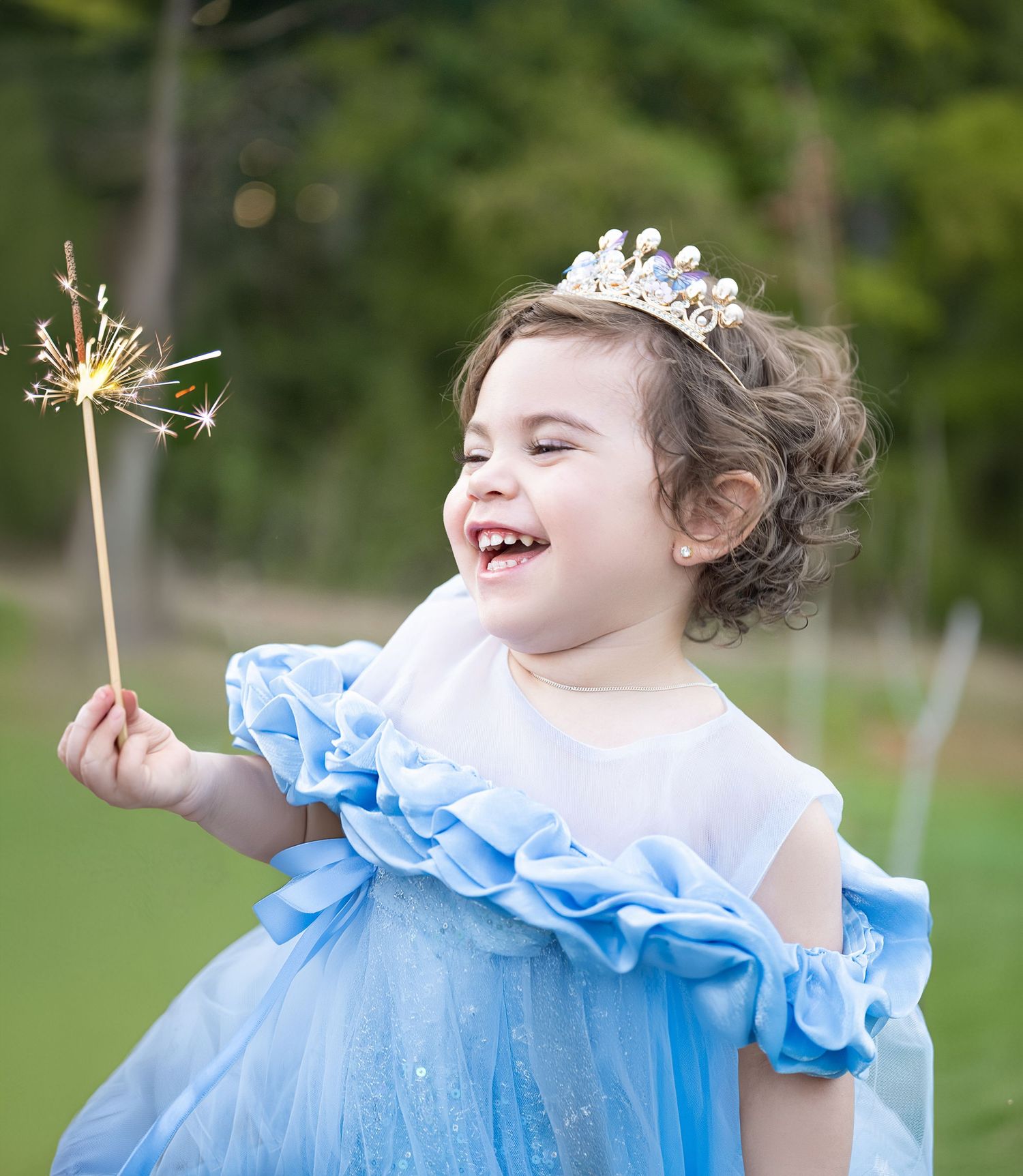 A magical moment with sparkler and blue ruffled dress in garden setting.