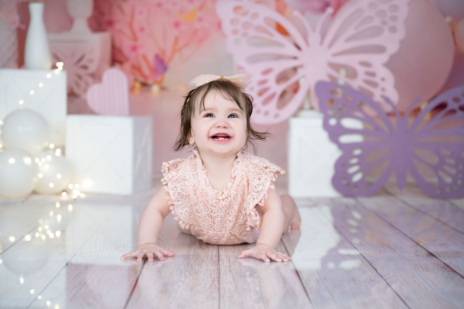 Pink studio setting with butterfly decorations and fairy lights on wooden floor.