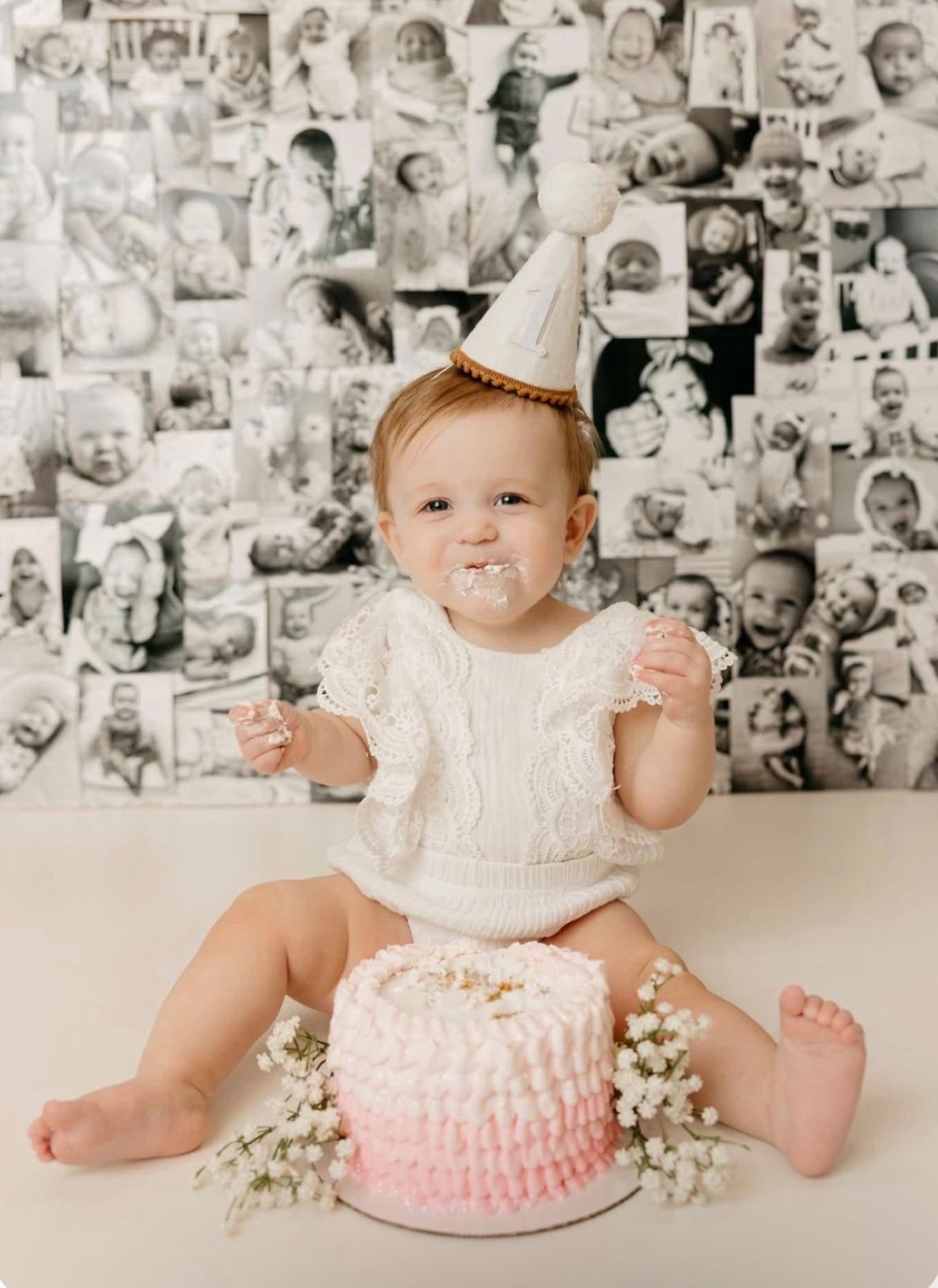 First birthday cake smash setup with vintage photo wall backdrop and pink ombre cake.