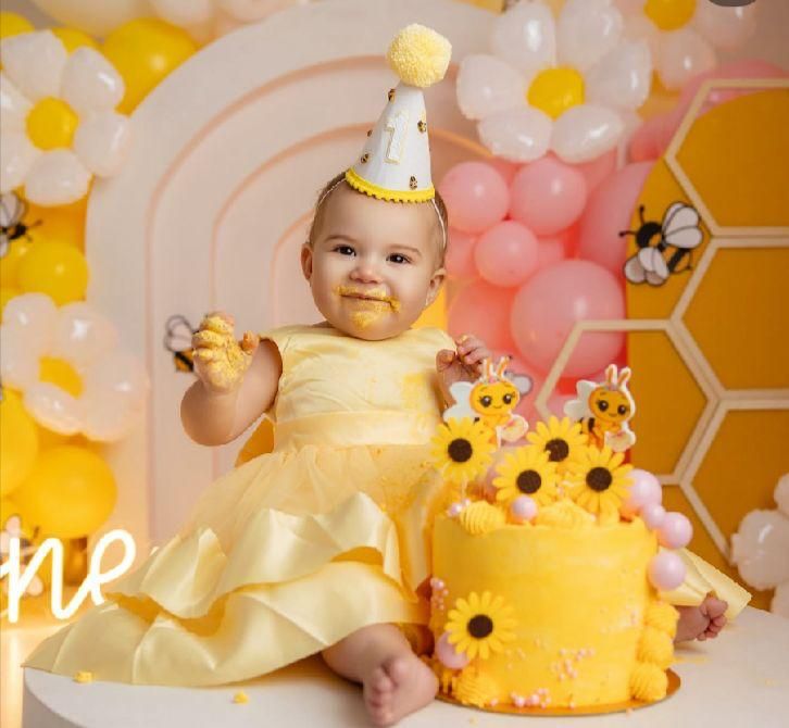 Yellow and pink balloon decorations with a honeycomb pattern create a festive backdrop for a birthday celebration.