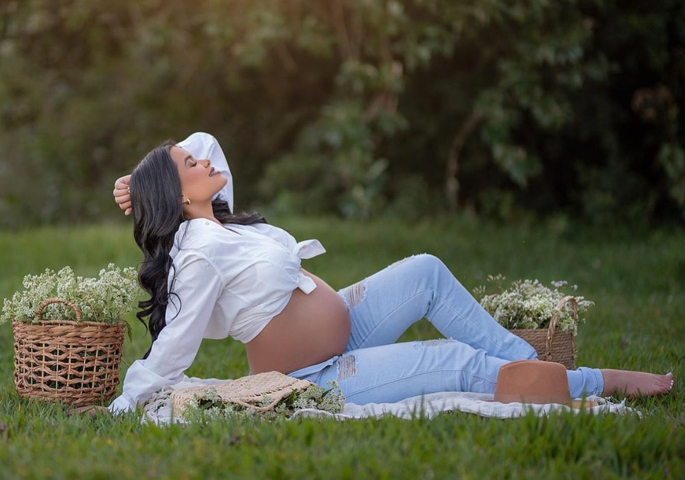 A couple relaxes together on a blanket during a romantic outdoor picnic in a grassy meadow.
