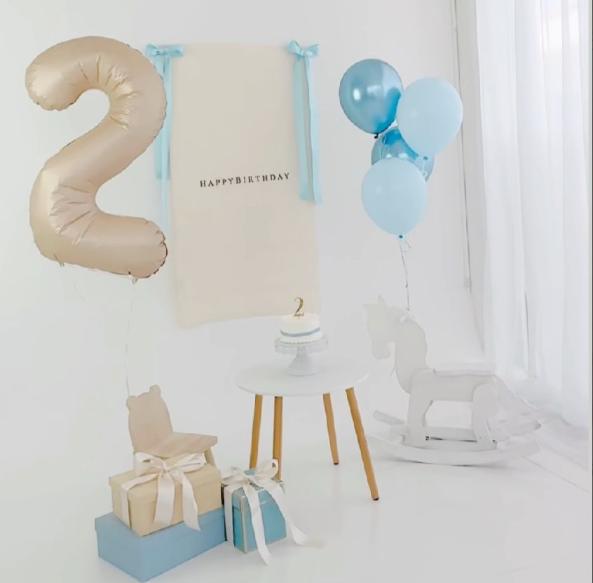 Elegant party setup with gold number 2 balloon and light blue decorations against a white backdrop.