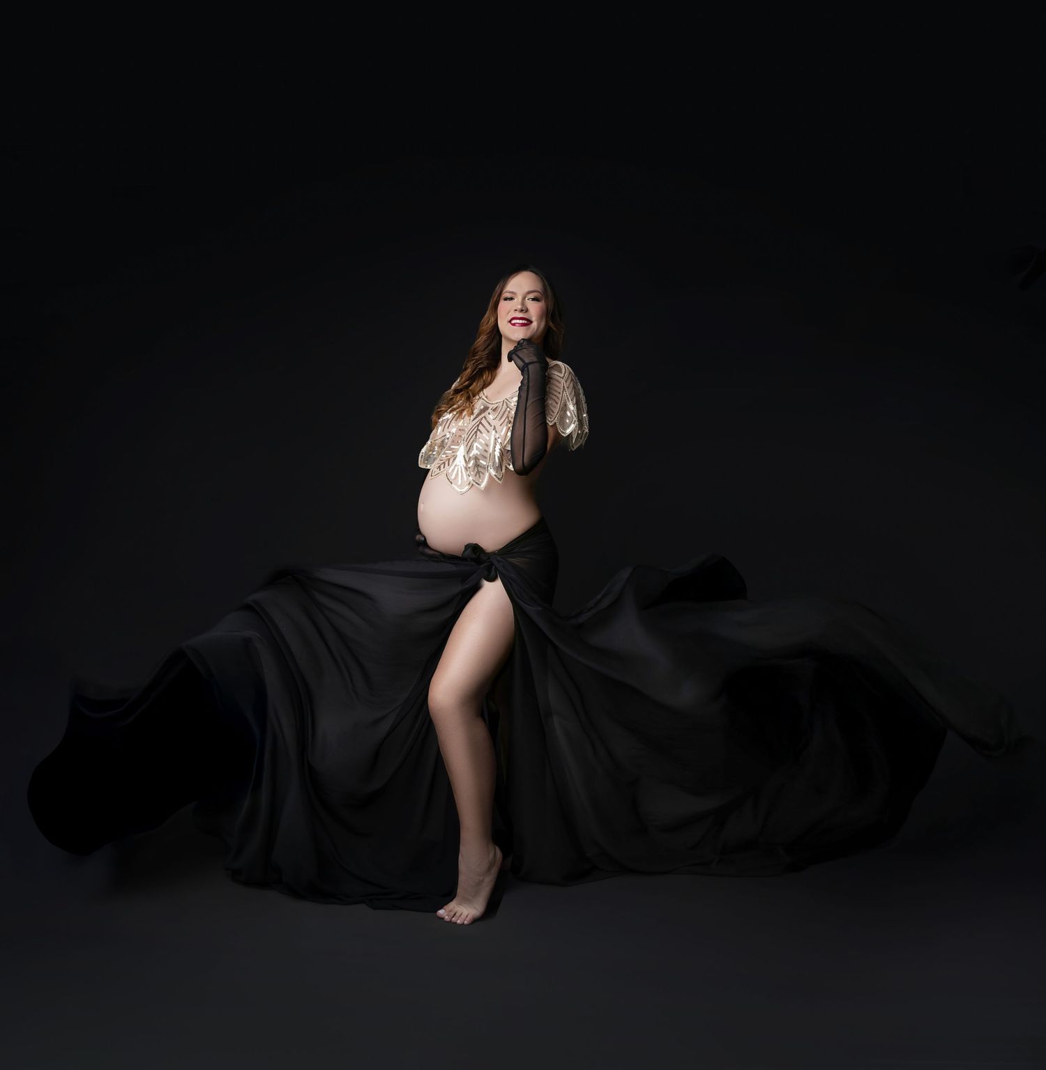 Artistic maternity photo series showing silhouette of pregnant woman in black dress against dark background.