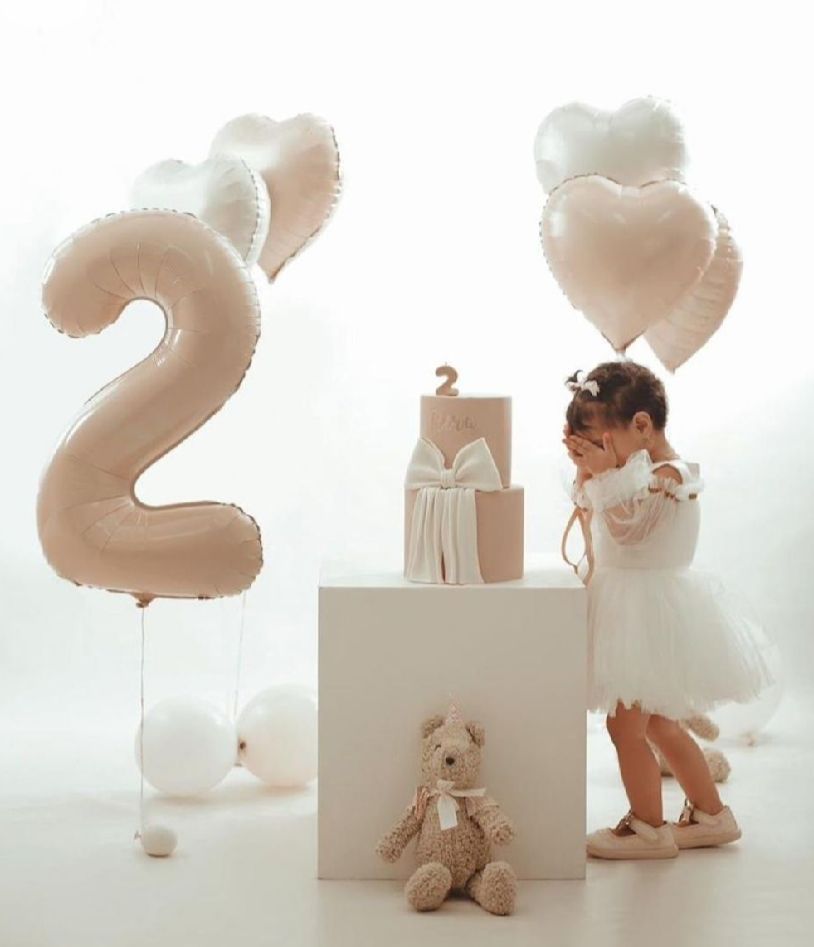 Minimalist white birthday setup with balloons, teddy bears and decorative elements on white background.