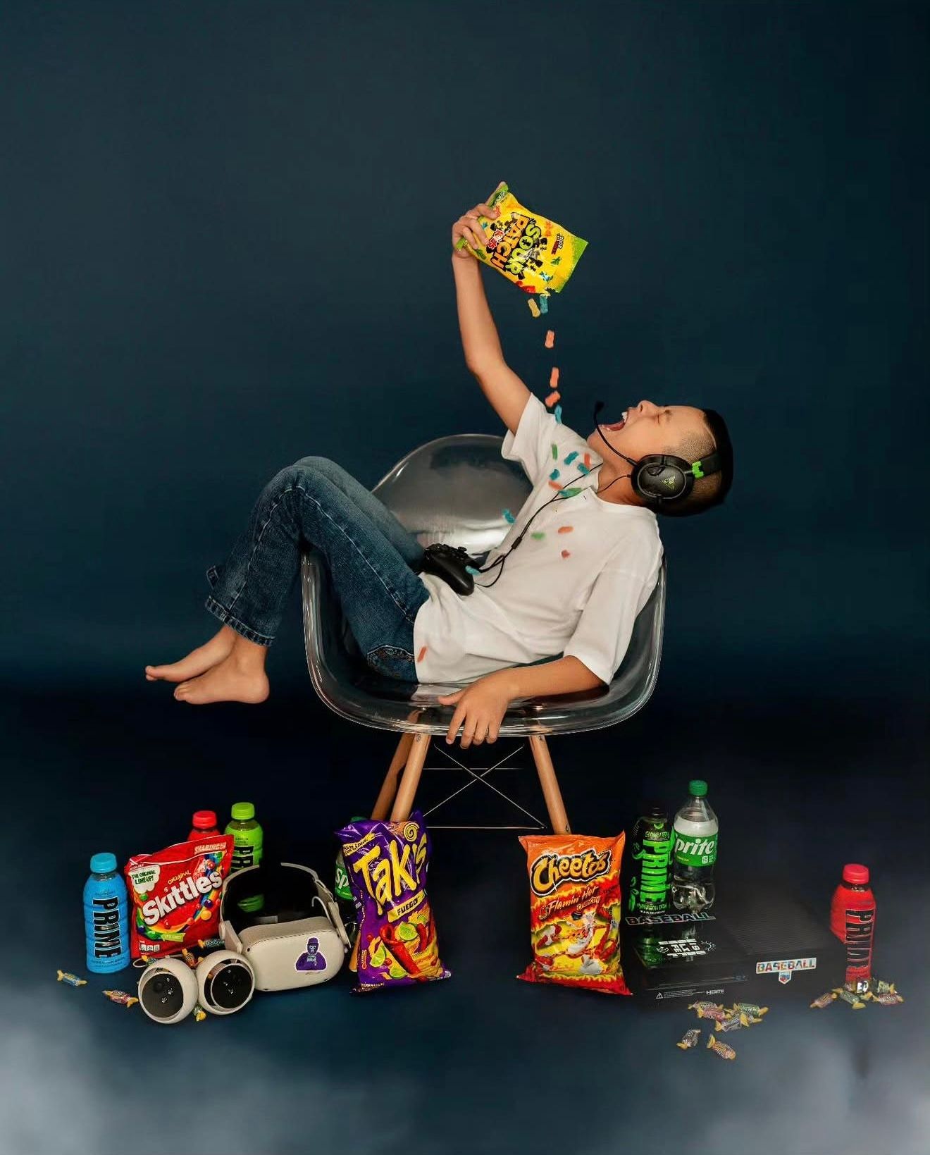 Person leaning back in chair with headphones, pouring Cheetos, surrounded by Takis, Skittles, and energy drinks.