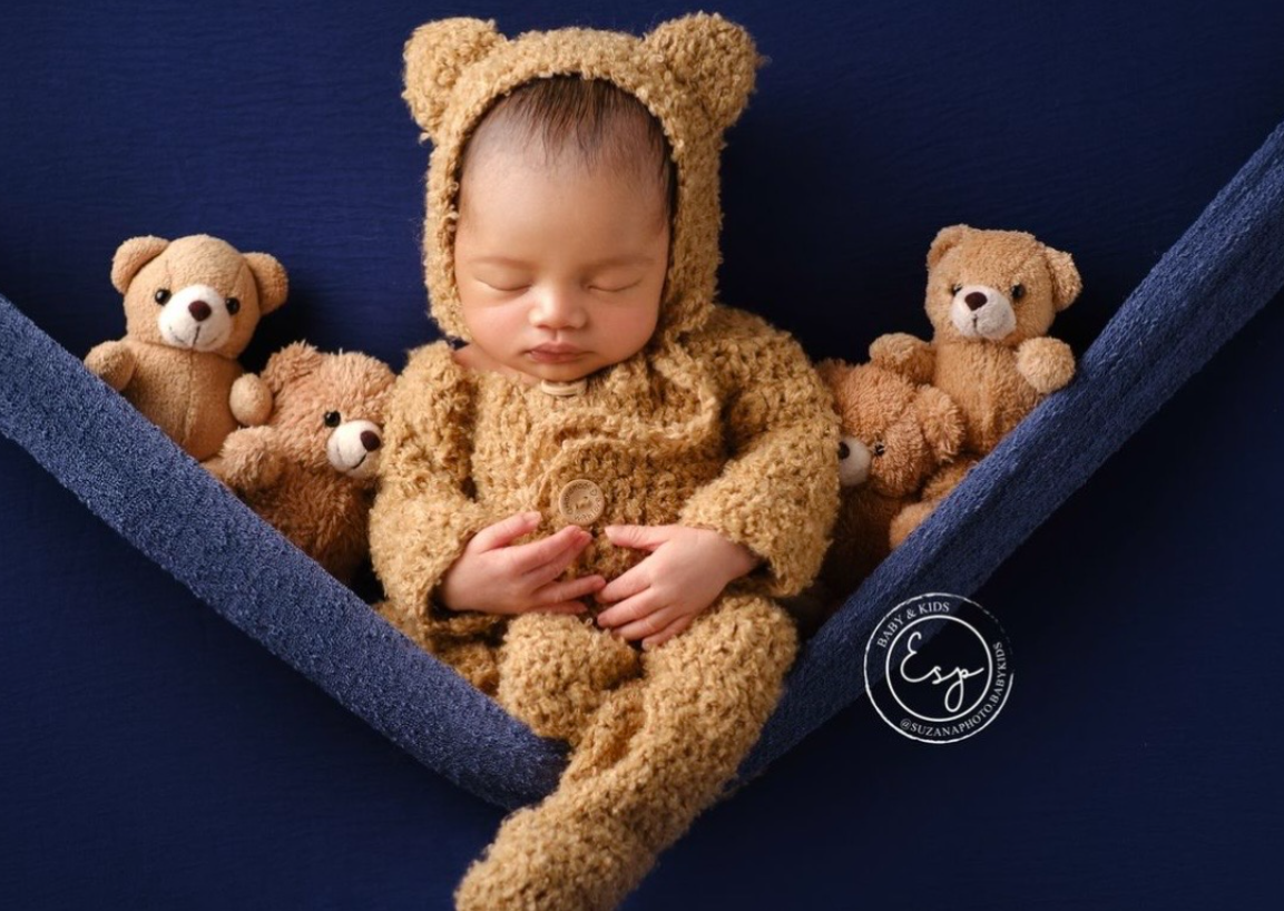 Sleeping baby nestled with brown teddy bears on dark blue fabric in a series of peaceful poses.