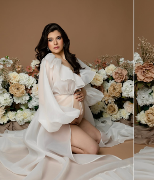 Romantic boudoir photo with soft lighting features white fabric draping and cream floral arrangements in the background.