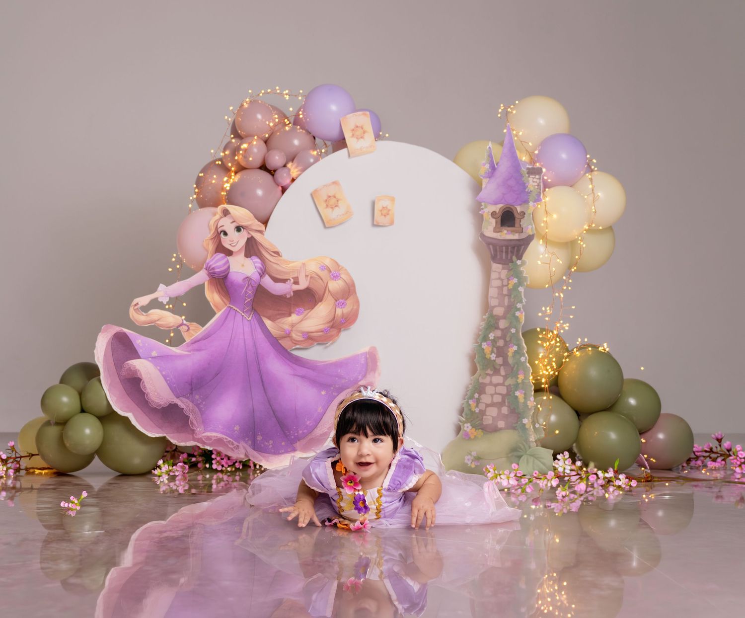 Baby girl in Rapunzel costume poses at a Tangled-themed first birthday party with balloons and princess backdrop.