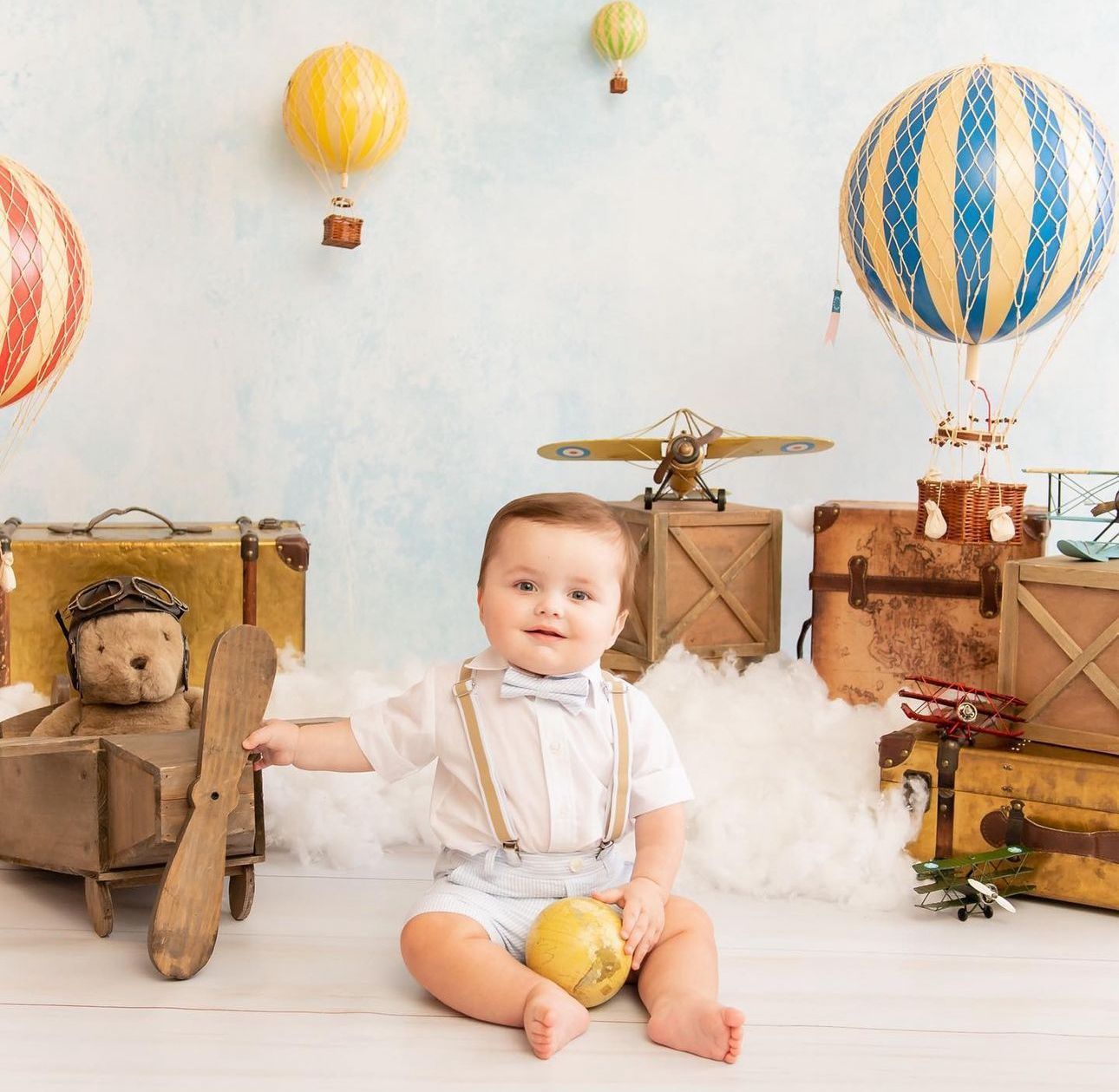 Vintage hot air balloon themed nursery setup with wooden crates and whimsical decorations in soft pastel colors.