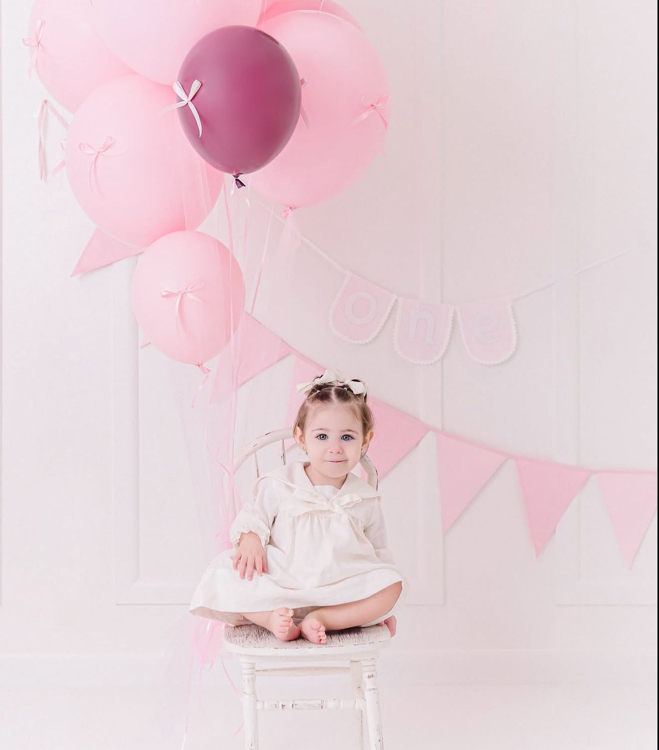 Sweet pastel pink party scene with pink balloons and bunting decorations against a light background.