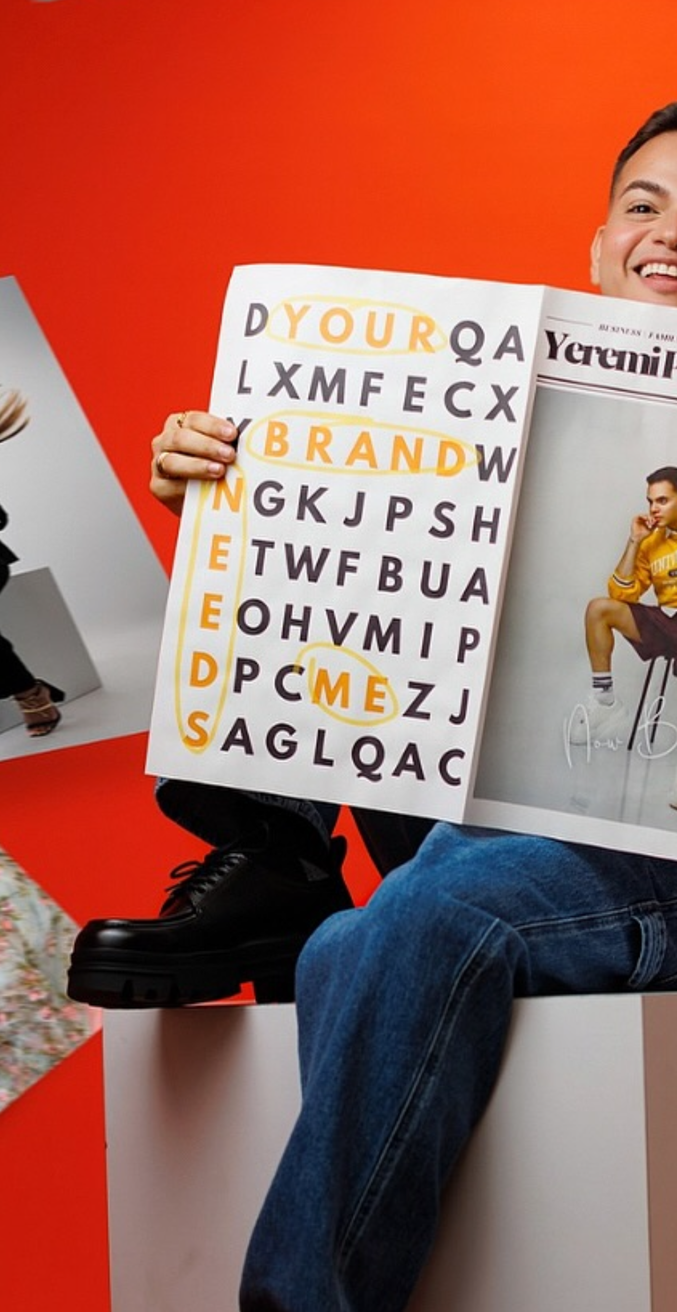 Person holding a magazine with a word search puzzle highlighting YOUR BRAND NEEDS ME against an orange background.