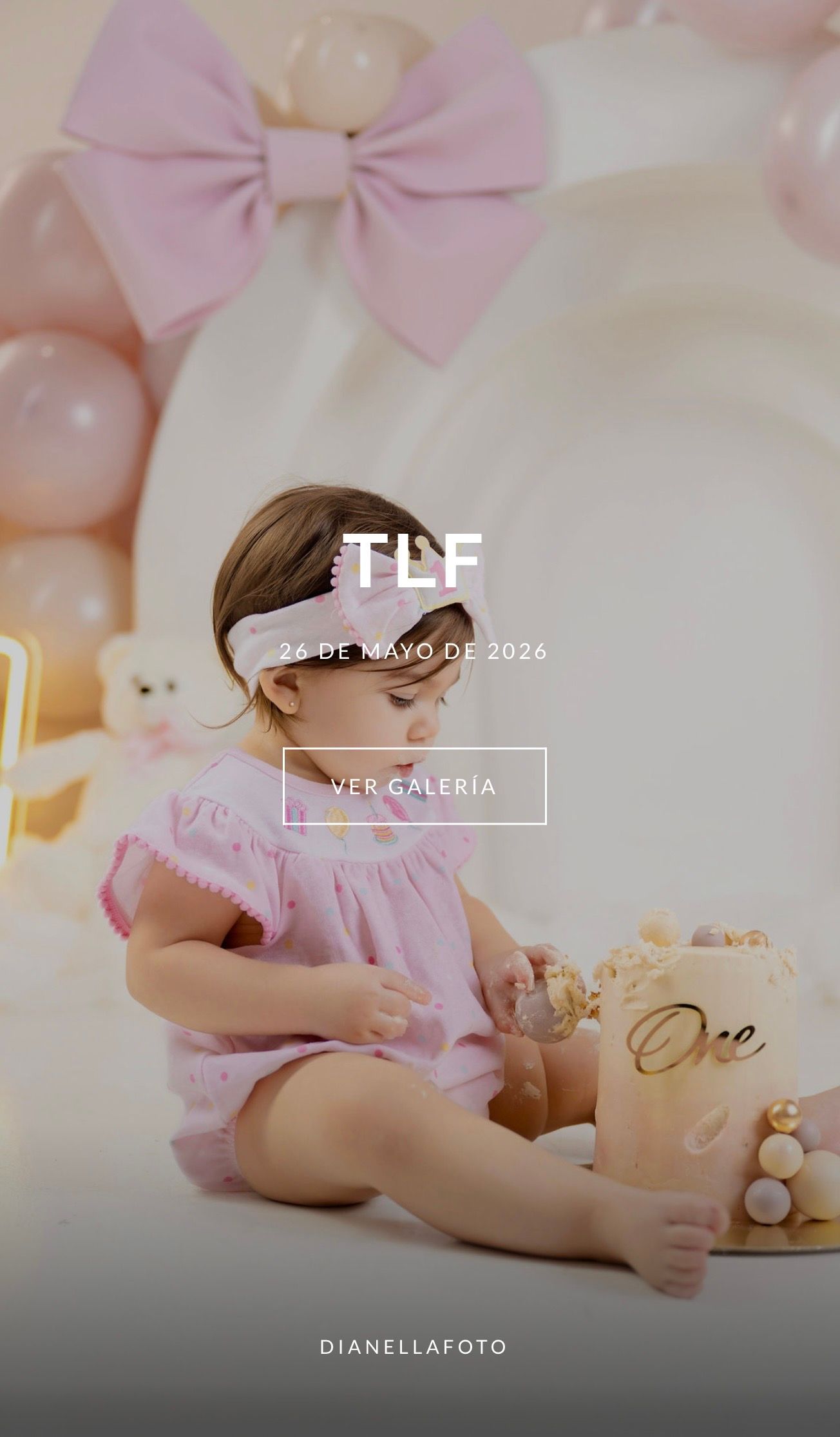 Baby girl in pink dress smashes first birthday cake surrounded by pink balloons and bow decorations at a TLF photo session.