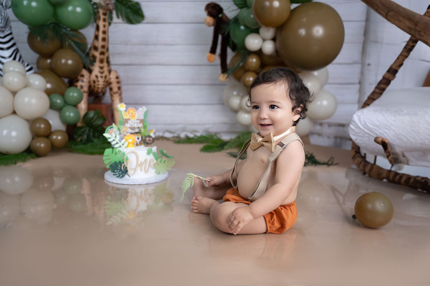 Safari themed first birthday setup with green and gold balloons and jungle animals.