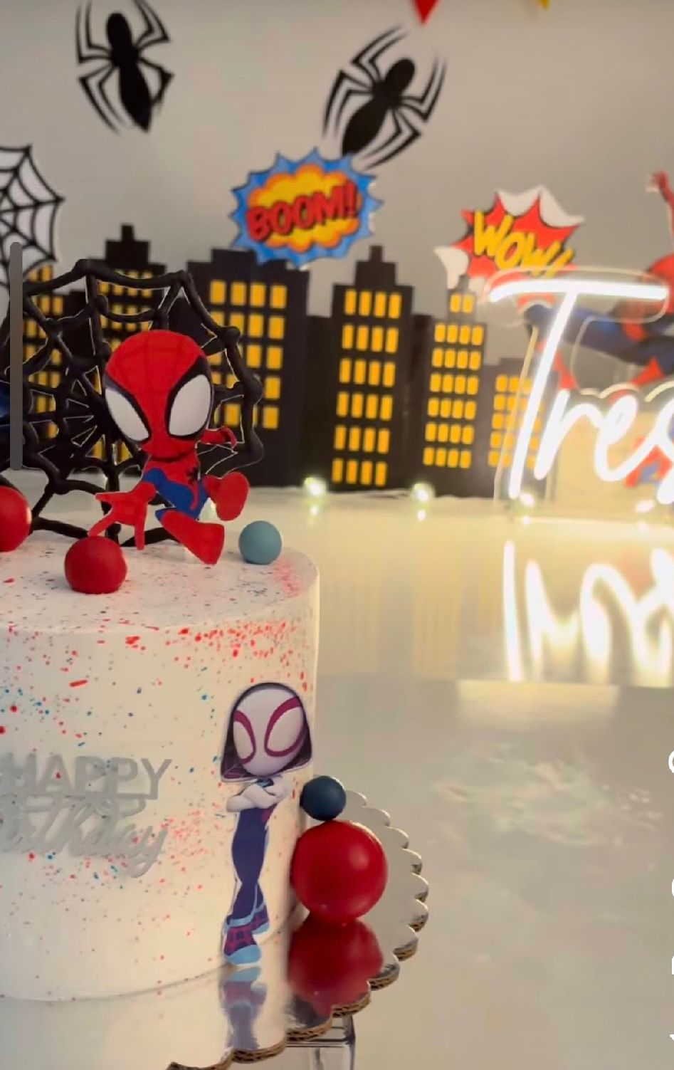A cityscape silhouette backdrop with Spider-Man decorations and party elements on a white surface.