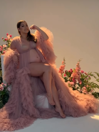 Dreamy maternity photoshoot featuring flowing dusty pink tulle gowns in warm sunset lighting.
