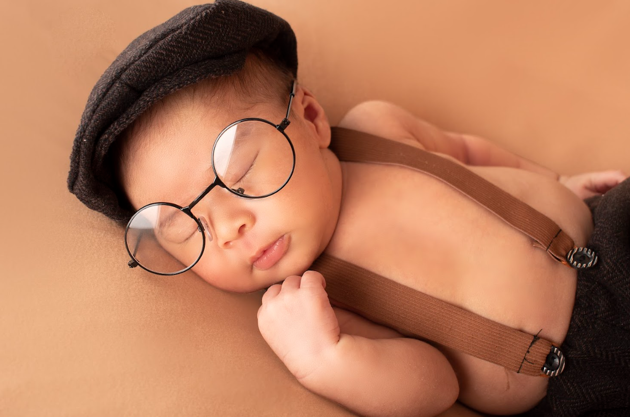 Newborn photography session featuring a sleeping baby in a peach-toned setting.