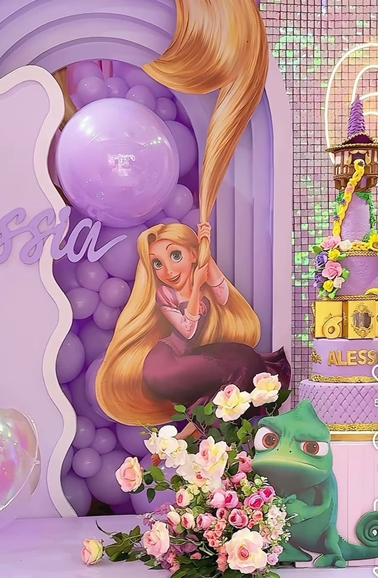 Rapunzel-themed birthday party decor with purple balloons, floral arrangements, and Pascal the chameleon cutout.