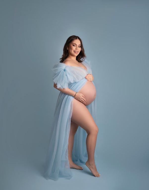 Maternity photo series showing a pregnant figure in a flowing light blue fabric against a gray studio backdrop.