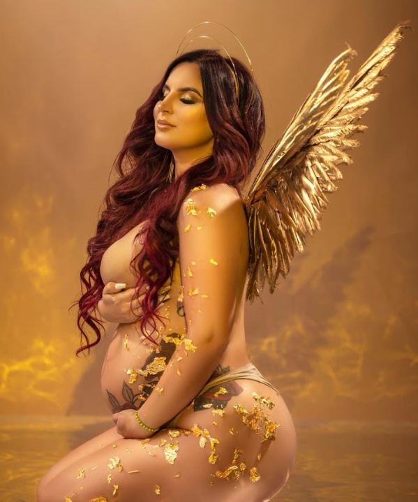 Fantasy portrait with golden wings and glitter in warm lighting against ethereal sunset backdrop.