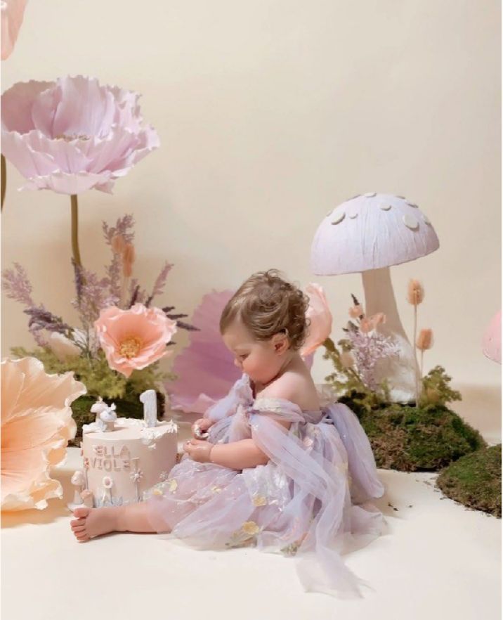 A series of dreamy pastel photographs showing a small child in a tulle dress posed with delicate pink flowers and moss.