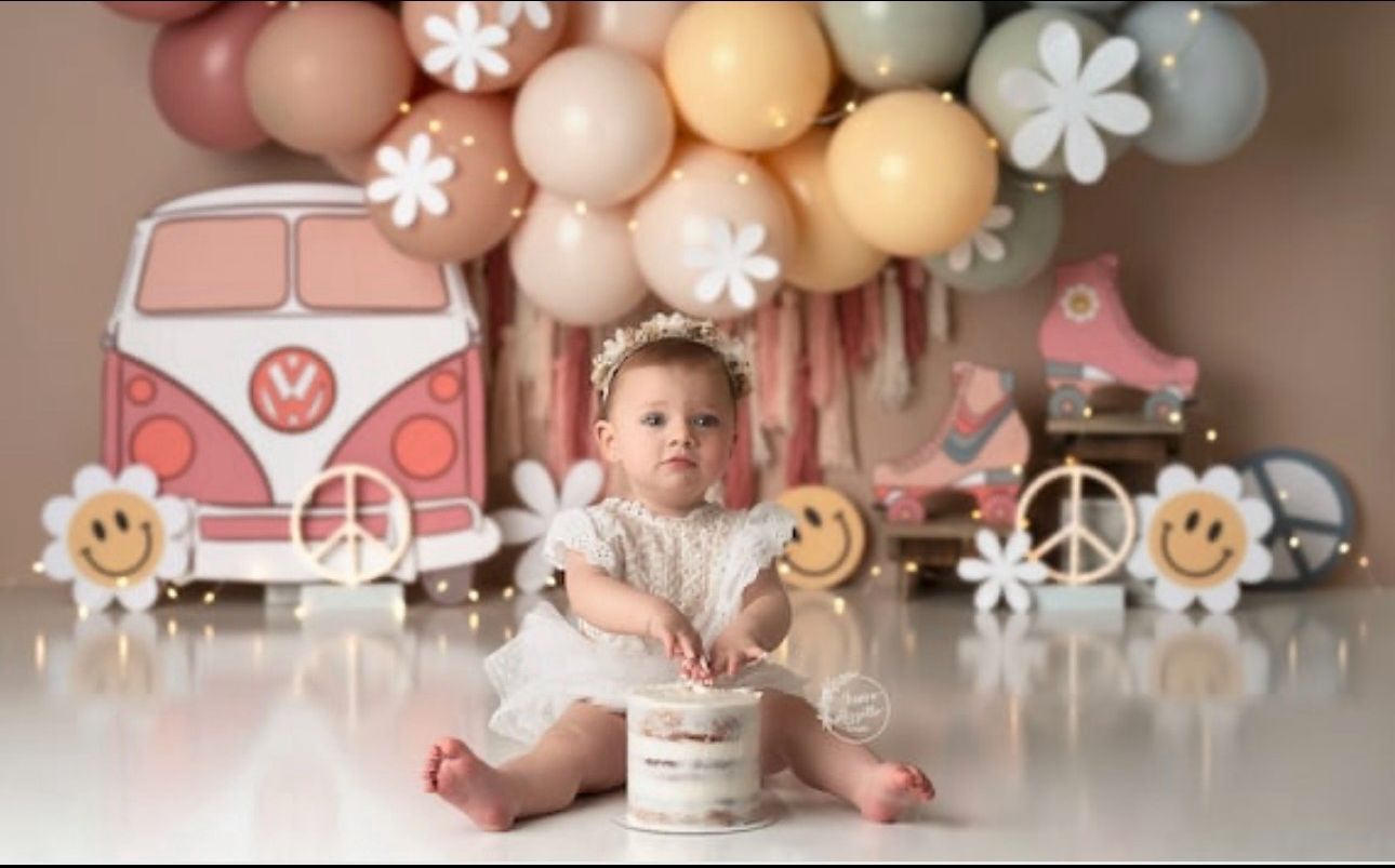 Pink and peach balloon arch with white floral accents and soft pastel decorations for a baby celebration.
